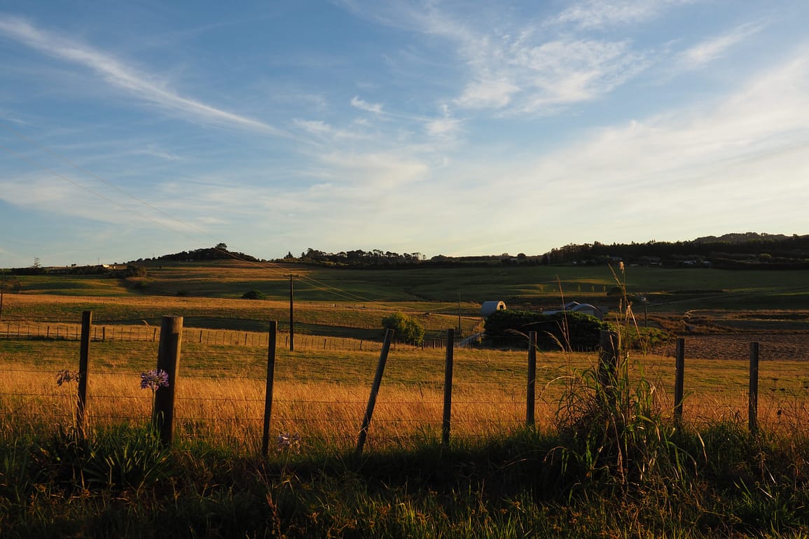 View over rural hills at sunset with a fence in the foreground